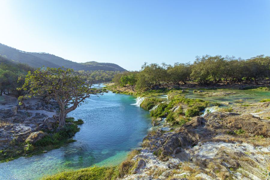 Turquoise rivier met watervallen en groene bomen bij Salalah